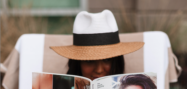 Woman with a hat on reading a magazine.